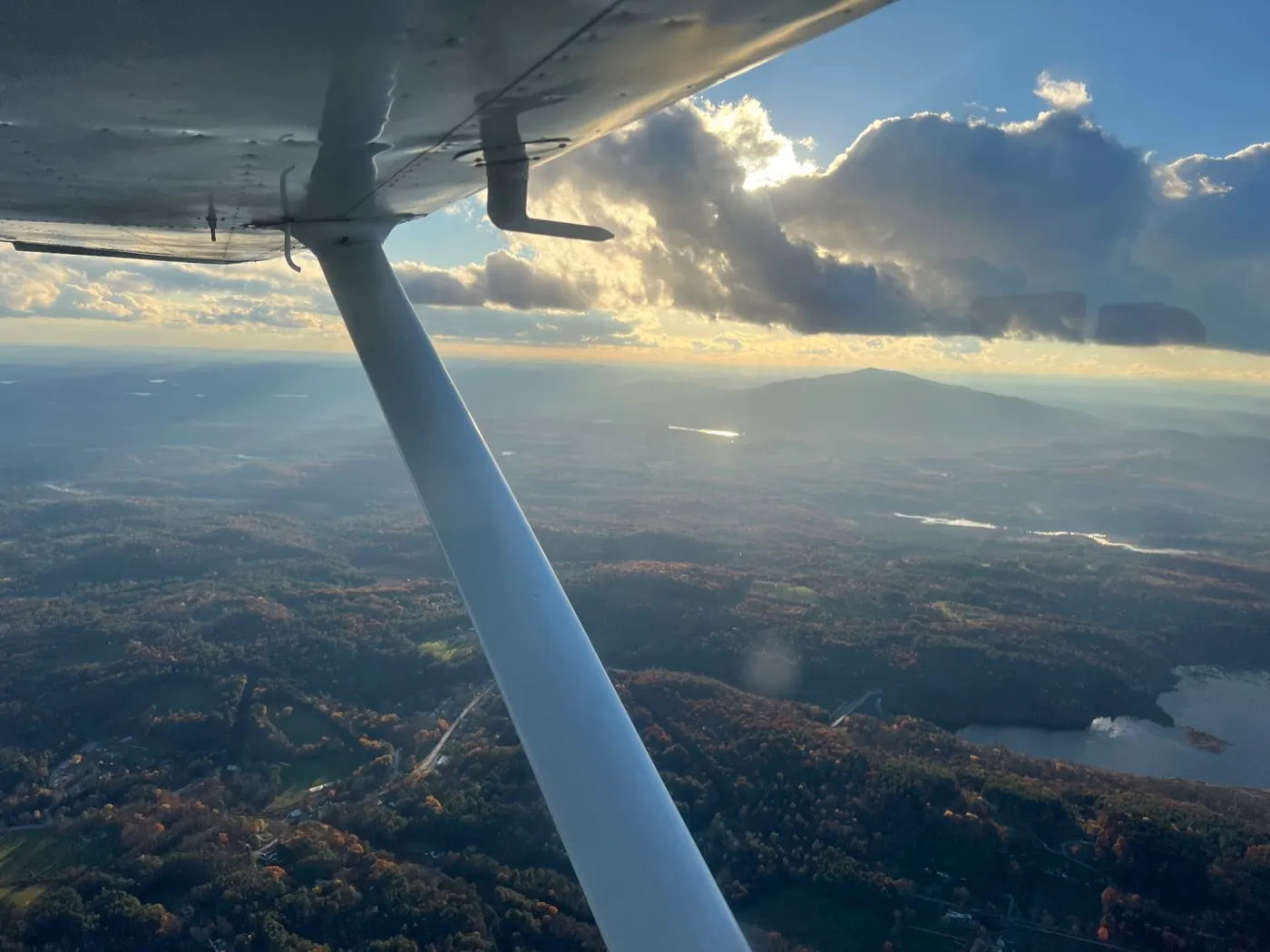 View from a small plane of Mount Monadnock under late-day clouds, the wing strut crossing the frame
